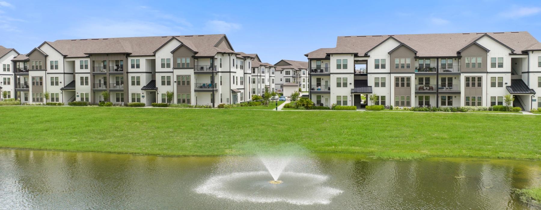 water fountains in large pond next to apartments